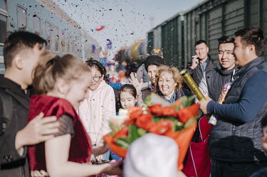 People celebrate a wedding with confetti and flowers on a train platform. The Kazakh marriage tradition requires several trips by the bride and groom. Here a newly married couple arrives in the groom'...