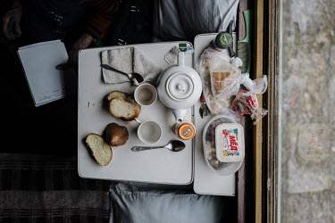 A folding table covered in food and drink in a train carriage.   Food plays an important social role in Kazakhstan. In the train compartment, food is shared between passengers, as a sign of respect...