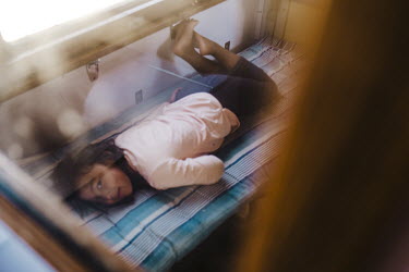 A girl lies on her bed in the sleeper carriage of a long distance train.