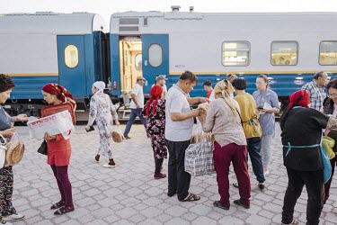 The train stops in Shykment and passengers buy bread from sellers on the platform.