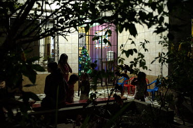 Women and children living in a shelter for women who have been victims of domestic abuse wait in the common room to pray the novena, a ritual of prayers and songs that they perform every night leading...