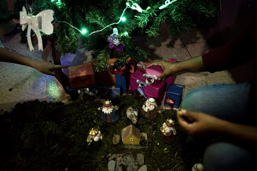 Children and mothers residing in a center for women who have been subjected to domestic vioelence decorate a Christmas tree.   Lago Agrio is a border city between Ecuador and Colombia and has one of t...