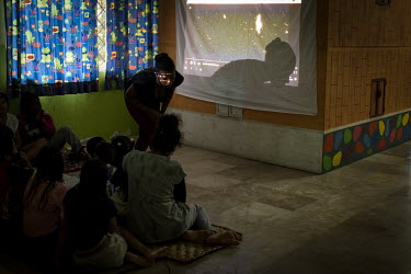 Children and mothers residing in a center for women who have been subjected to domestic vioelence sit on the floor while watching a Christmas film.   Lago Agrio is a border city between Ecuador and Co...