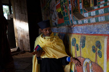 A young man show narrative art paintings of battles and martyrdoms from Ethiopia's past in Betre Mariam church on the Zege peninsula, embellished with depictions of flora.
