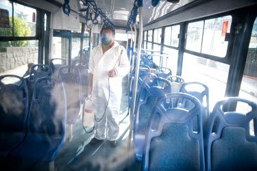 A worker disinfects the interior of a bus in preparation for medical personnal to board in Quito.