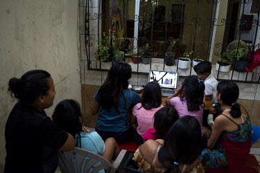 Women and girls living at a shelter for women who have suffered domestic abuse gather to watch television.