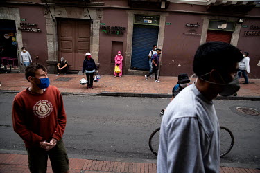 People wait to enter a supermarket in Quito while observing social distancing and wearing masks.