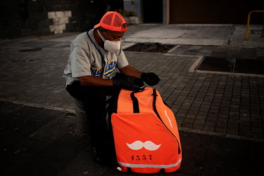 A delivery driver sits and waits for his next job during a covid lockdown in Quito.