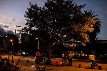 Home delivery riders wait for their next job in an empty downtown area of Quito during a covid lockdown.
