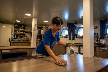 Deckhad Yei Hsuan Huang cleans the mess after lunch on the Greenpeace vessel Arctic Sunrise.