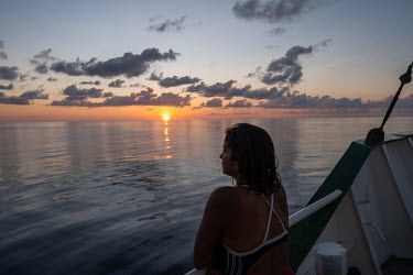 Climate activist Shaama Sandooyea watches the sunset from the deck of the Greenpeace vessel Arctic Sunrise near the Seychelles.