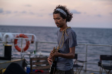 Campaigner Dan Jones plays guitar after work on the Greenpeace vessel Arctic Sunrise, during an expedition to survey the Saya de Malha Bank in the Indian Ocean.