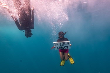 Climate activist Shaama Sandooyea holds a sign in support of the climate strike during a visit of the Greenpeace vessel Arctic Sunrise to the Saya de Malha bank in the Indian Ocean.