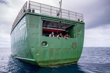 People look out from the poop deck of the Greenpeace vessel Arctic Sunrise in the Indian Ocean.