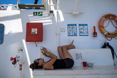 Deckhand and ship's medic Laia Pascual reads a book during a break on the Greenpeace vessel Arctic Sunrise.