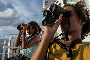 Dan Jones and climate activist Shaama Sandooyea watch a pod of spinner dolphins from the Greenpeace vessel Arctic Sunrise during a sightings survey of the Saya de Malha Bank.