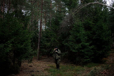 A border guard in the forest by the border.   Thousands of migrants attempted to cross into Europe along the Poland Belarus border in the autumn of 2021. By the last week of October six migrants had d...