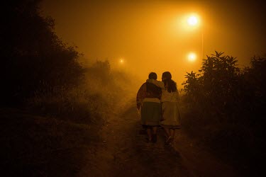 Two Karanki women walk together in the moors near their community.
