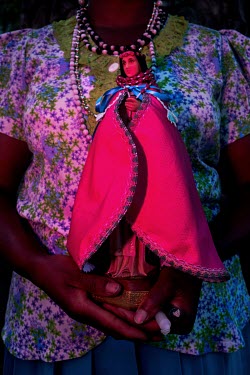 A woman carrying a statue of the Virgin of Mercy during a pilgrimage of Afro-Ecuadorians whose beliefs blend Catholic and African ancestral rituals. The religious celebrations and the 'santoral' are c...