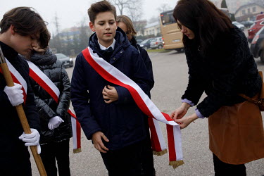 Local youths have a sash of the Polish flag attached by their teacher before a mass for the anniversary of Polish Independence in Sokolka. The town is situated near the state of emergency zone by the...