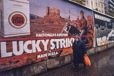 A woman walks past a billboard advertising Lucky Strike / Made in USA.