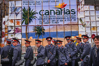 Police cadets line up in front of a sign advertising Canary Island holidays. The caption reads 'A Warm Nature' at a time when foreign travel was first becoming possible for ordinary Russians who could...