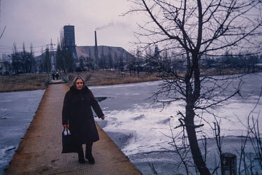 A woman walks on a bridge over a pond heavily polluted by run off from the coal mine in the background. The Donetsk region later became the center of conflict between ethnic Russians and the rest of U...