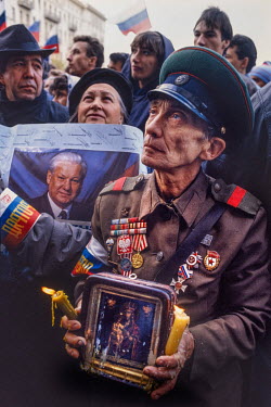 An elderly supporter of Russian President Boris Yeltsin wearing wartime medals and an army uniform holds a religious icon in front of the Russian Parliament after the failure of the 1991 coup attempti...