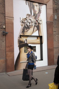 A fashionably dressed young woman walks past advertising for a designer boutique on Moscow's main street.
