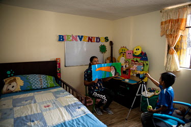 Graciela Almachi is a teacher who has to practice virtual education due to the Covid 19 pandemic. She is recording a class video with the help of her 6 year old son in a makeshift classroom at home.