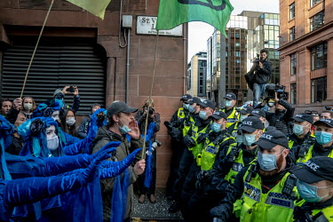 Climate activists dressed in blue costume sface a line of police during a â��Greenwash' march through central Glasgow. Police closed roads and encircled the activists, causing groups to break away an...