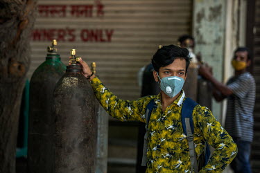 People in need of oxygen for Covid 19 patients wait with empty cylinders to be refilled, outside the shop in Delhi.