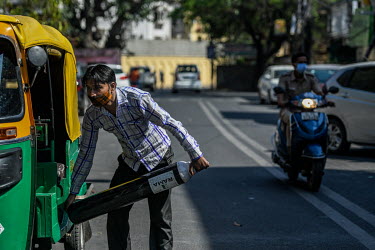 A man unloads an empty oxygen cylinder from a taxi, hoping to exchange it for a full one at a shop in south Delhi.