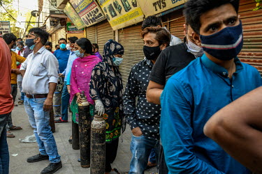 People queue for oxygen refills at a shop on Delhi, before returning to relatives who are home quaratined.