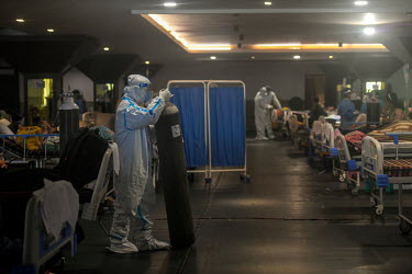 Health workers in personal protective equipment move oxygen cylinders for patients in a temporary medical facility set up during the Covid 19 pandemic in Delhi.