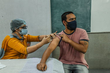 A young man receives his first dose of a Covid 19 vaccine at a government school in Delhi. This is part of phase 3 of the vaccination program In India, which aims to inoculate 18-44 year olds. In Delh...