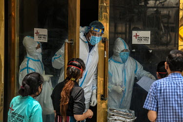 Health workers in personal protective equipment care talk to relatives in a temporary medical facility set up during the Covid 19 pandemic in Delhi.