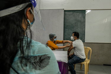 A young man receives his first dose of a Covid 19 vaccine at a government school in Delhi. This is part of phase 3 of the vaccination program In India, which aims to inoculate 18-44 year olds. In Delh...