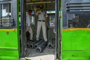 Hospital staff with the help of policemen unload oxygen cylinders from a Delhi Transport Bus.