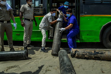 Hospital staff with the help of policemen unload oxygen cylinders from a Delhi Transport Bus.