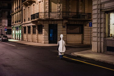 A musician walking through the deserted streets of the Quartier des Banques, carrying a double bass. She is heading to the nearby Haute école de musique de Geneve, during Covid-19 lockdown.