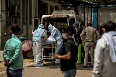 Healthworkers in personal protective equipment carry the body someone who has died due to Covid 19 from an ambulance to the mourtury of LNJP hospital in Delhi.
