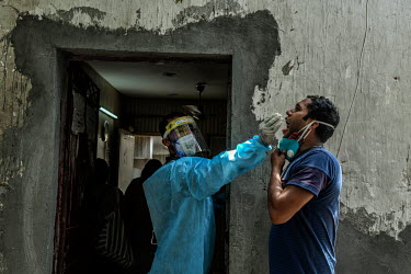 A young man has a Covid 19 test performed by a worked in personal protective equipment in south Delhi.
