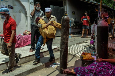 An older woman with very low oxygen saturation is carried to receive free oxygen support at a gurdwara, a place of assembly and worship for Sikhs, amidst the spread of the coronavirus disease, in Delh...