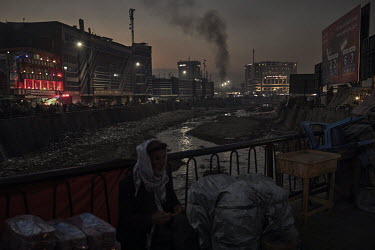 A man sits on a bridge over the Kabul river running through the center of the city.