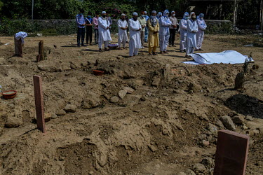 Relatives pray beside the body of a man who died from coronavirus, during his funeral at a graveyard in New Delhi, India.