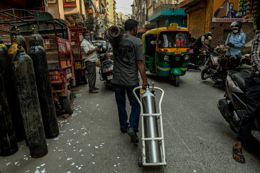 A man carries old and new oxygen cyclinders at a refilling center in Delhi during the coronavirus pandemic.