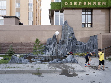Children play with water next to fake rock and a fountain in the eastern outskirts of the city.