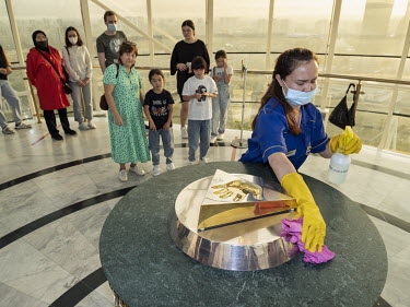 A woman cleans around the golden cast of the hand of former president Nursultan Nazarbayev in the iconic Bayterek Tower while visitors stand in line to put their hands in the cast. Those who place the...