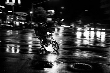 A food delivery rider working at night in the rain.